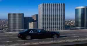 黒のロールス・ロイス ファントムが高層ビルの都市高速道路を走行するシーン